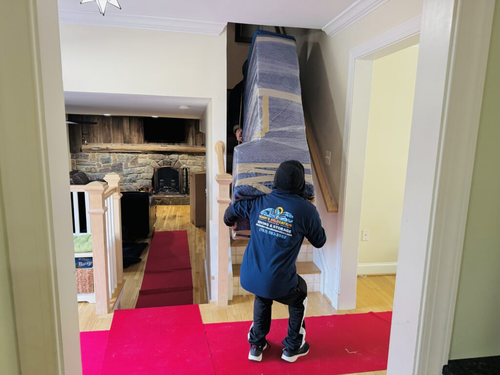 Movers carrying a large cabinet through the front entrance of a townhouse during a residential move